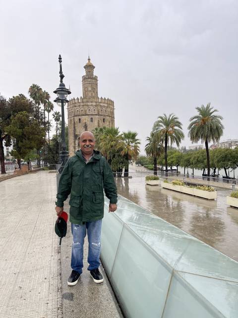 Person smiling in front of a historic tower.
