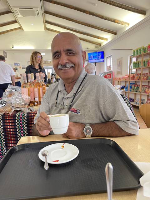 Person holding a small cup in a cafe setting.