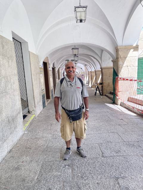 Person standing in an arcade with arched architecture.