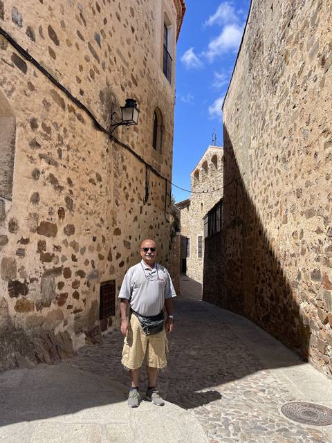 Person in a stone-walled street in historic setting.
