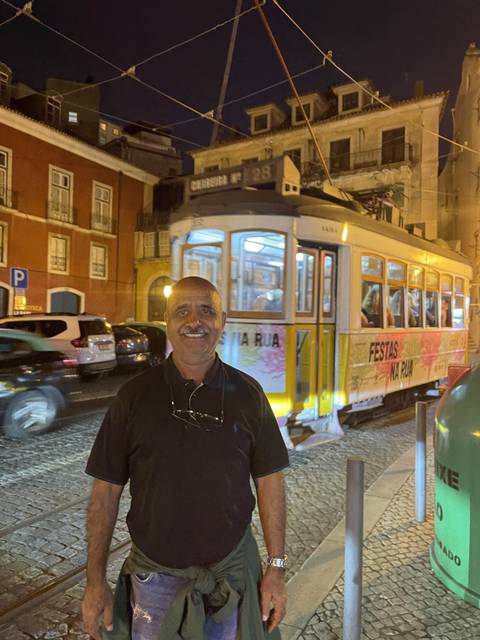 Person standing with a tram at night in a city.