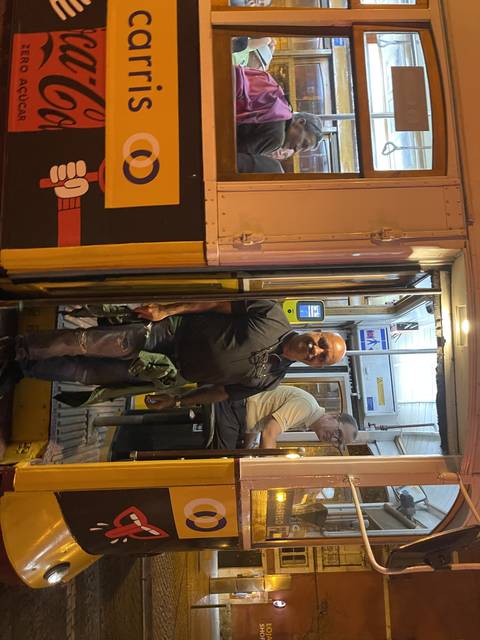 Person posing with a tram at night.