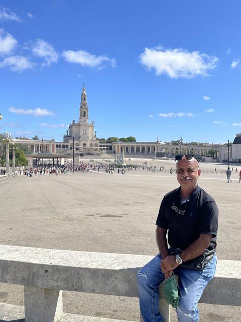 Person posing at a large plaza with a cathedral in the distance.