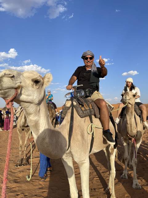 Person riding a camel in a desert landscape with clear sky.
