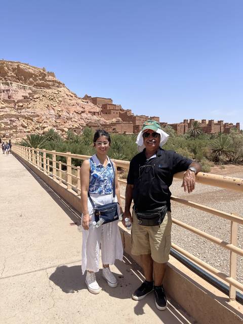 Two people posing on a bridge with an ancient town in the background.