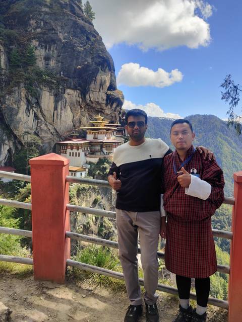 Two people posing with a view of a monastery.