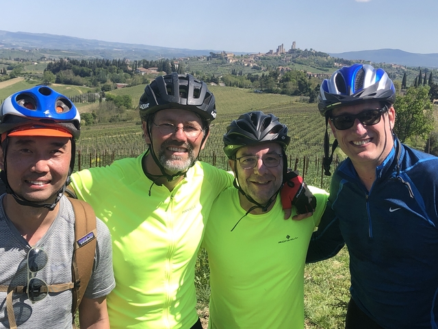 Four men with bicycles posing in a vineyard landscape.