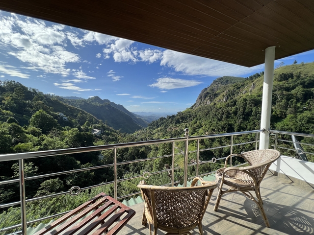 Mountainous view from a balcony with chairs.