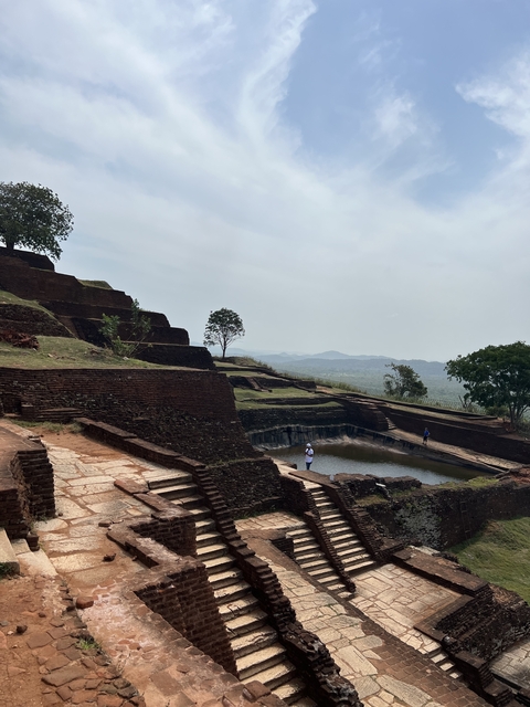 Ruins on a hill with people walking around.