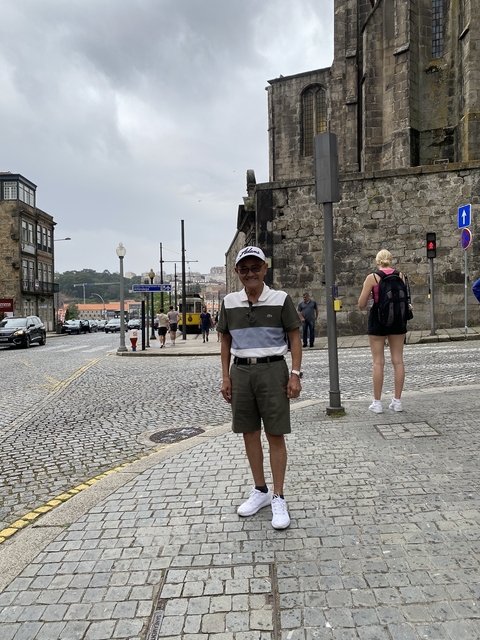 Elderly man standing on a busy urban street.