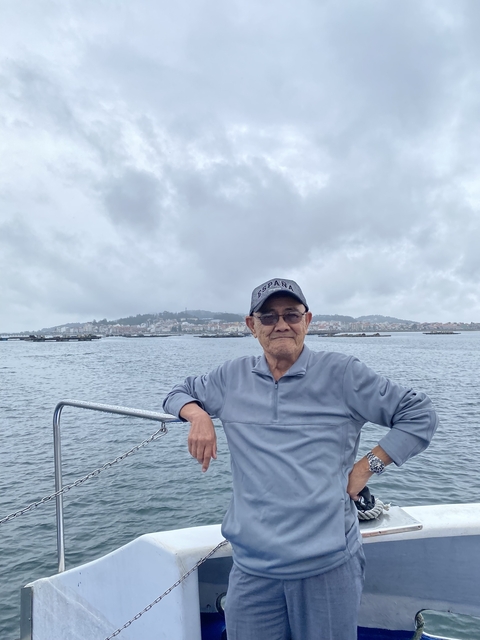 Man standing on a boat with a cityscape in the distance.
