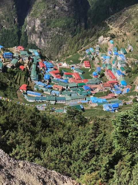 Aerial view of colorful rooftops cascading down the slopes of Namche Bazaar surrounded by greenery
