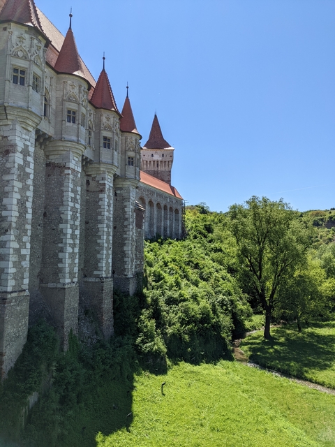 Stone fortress with red roofs and lush vegetation around.