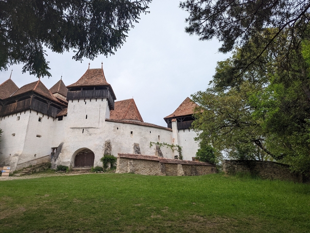 Fortified church with red roofs surrounded by greenery.