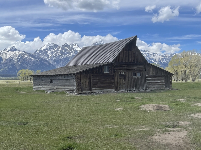 Rustic barn with mountains in the background.
