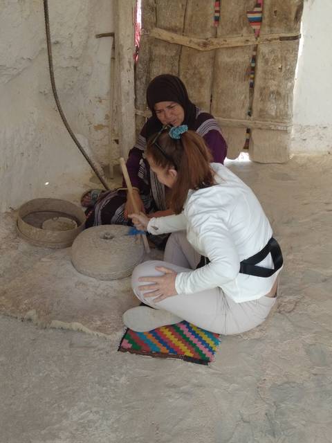 Two women involved in traditional activity inside a home.