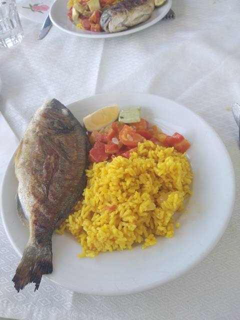 Plate of cooked fish with rice and vegetables.
