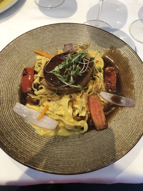 A gourmet dish of pasta with vegetables and meat.