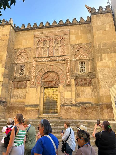 Tourists visiting an intricately decorated wall with arches.