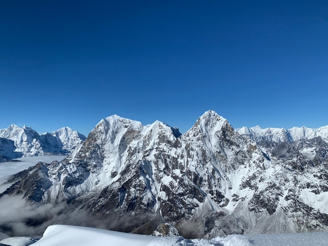 Panoramic view of jagged, snow-capped Himalayan mountains against a clear cobalt sky