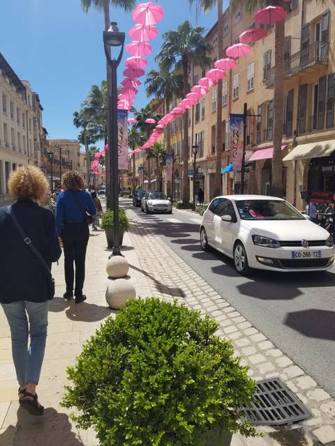 Street scene with pink decorations and cars; people walking.