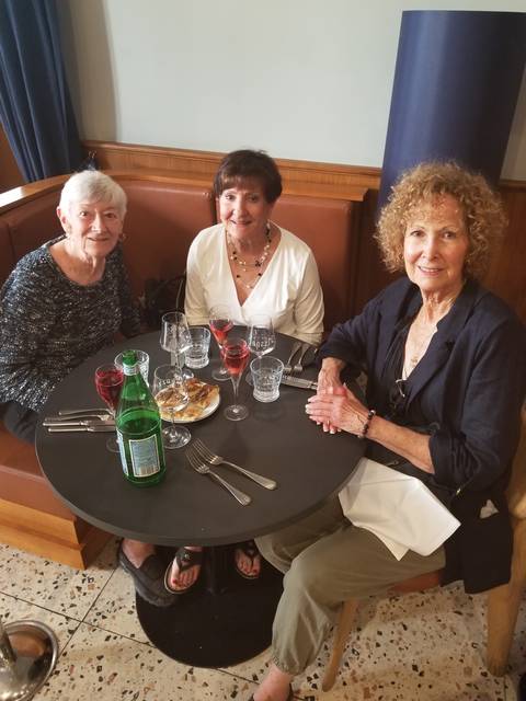 Three women sitting at a dining table indoors.