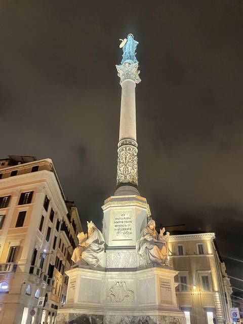 Statue of Mary on a column at night.