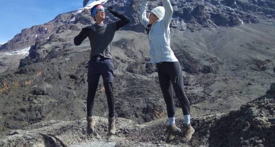 Two people jumping enthusiastically against a mountainous backdrop.