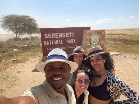 Group of people at the entrance of Serengeti National Park with a sign.
