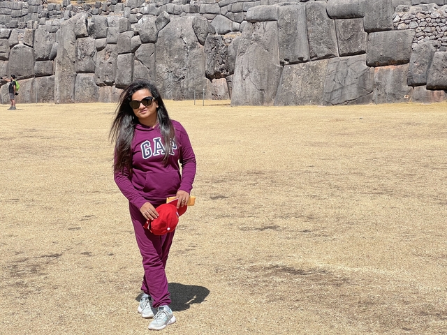 Person standing on a dry landscape in front of ancient stone formations.