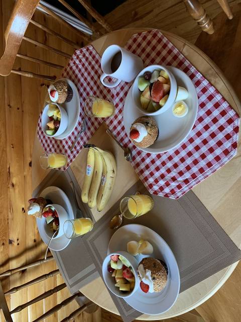 Breakfast table setup with fruit, muffins, and juices.