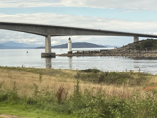 Bridge with a lighthouse by the shore.