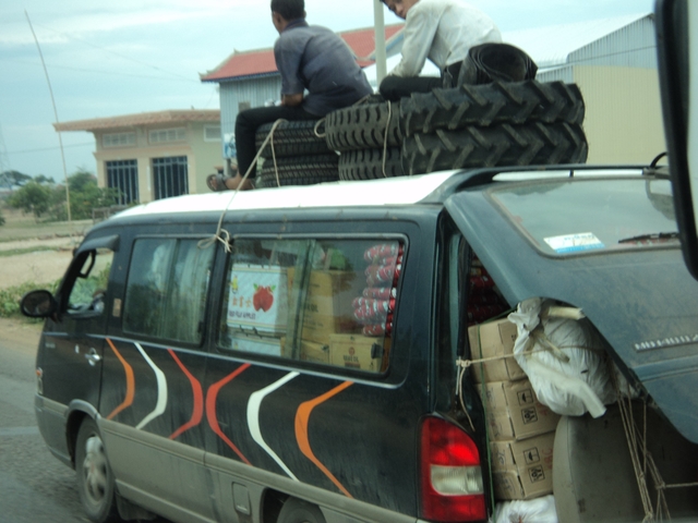 Overloaded van carrying goods and passengers on the roof.