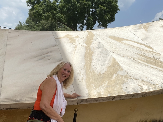 Woman examining a sundial at a historical site.