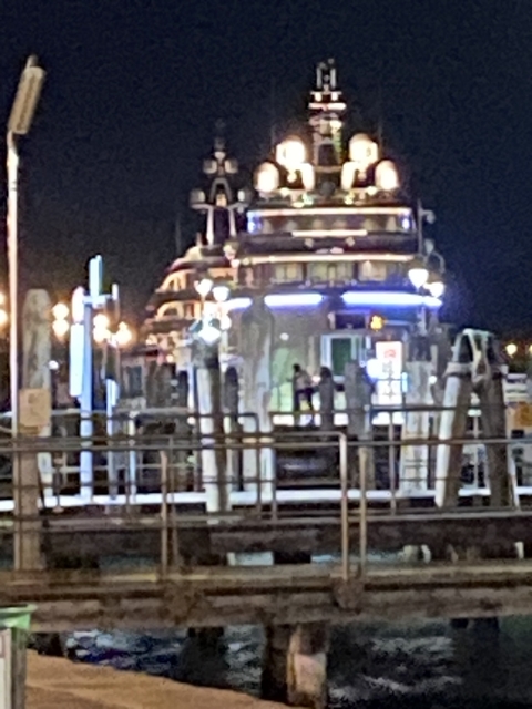 Night view of a docked ship with bright lights.