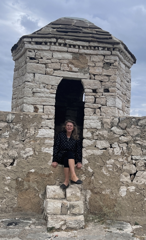 Person sitting inside an old stone structure.