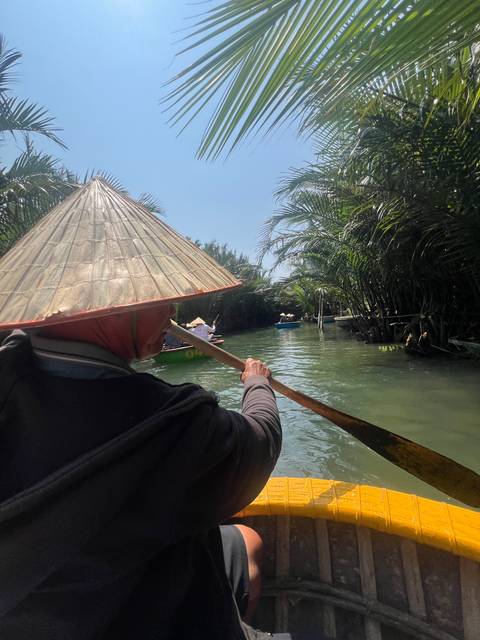 Person paddling a boat on a river surrounded by palm trees.