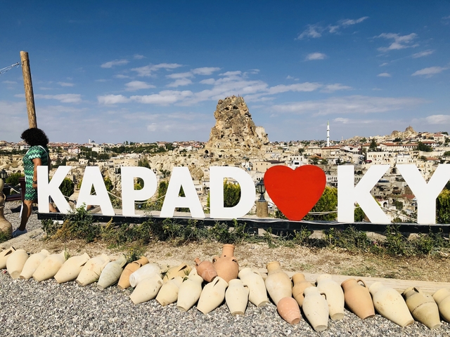 View of rock formations with vibrant Kapadokya sign.