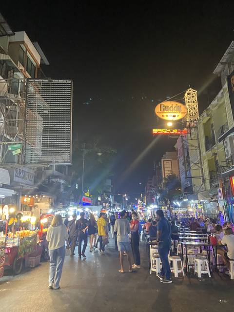 Night market scene with many people and neon signs.