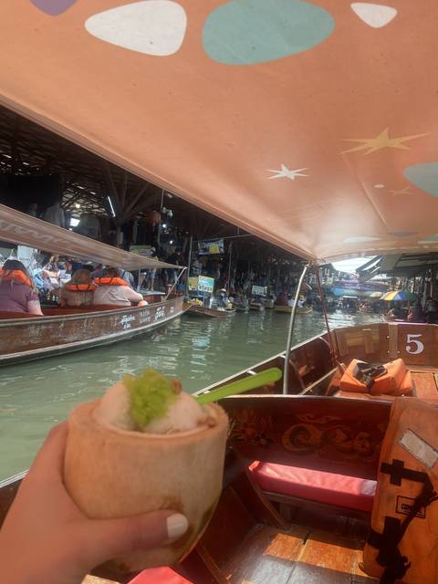 Floating market scene with boats and a drink.