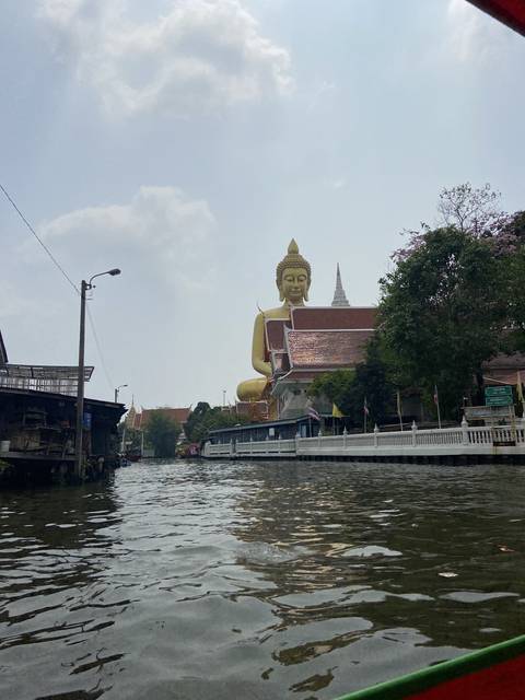 View of a large reclining Buddha statue from the water.