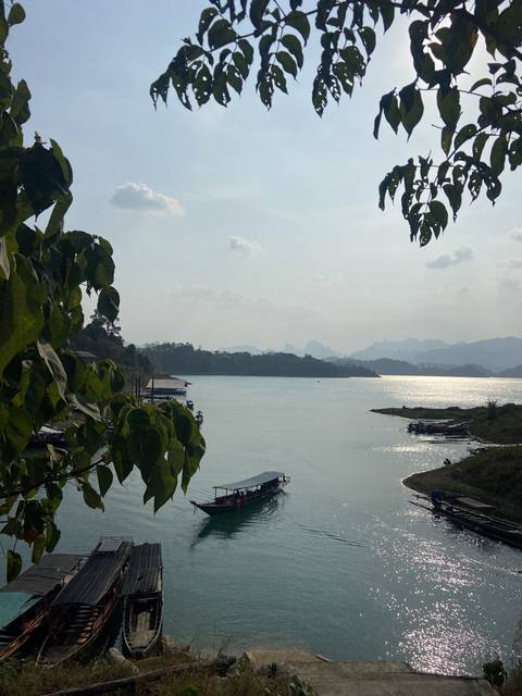 Calm lake scene with boats and hills.