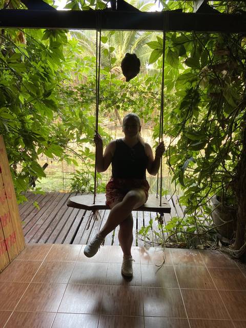 Person sitting on a swing with foliage.