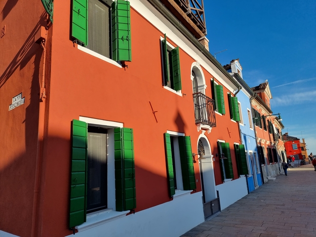 Colorful buildings with green shutters under blue sky.