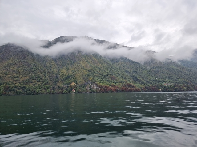 Lush mountains with clouds and a lake in the foreground.