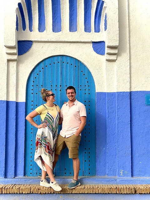 Two people in front of a blue arched door.