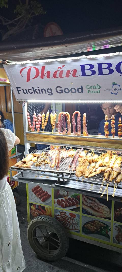 Street food stall with grilled items and prominent signage.