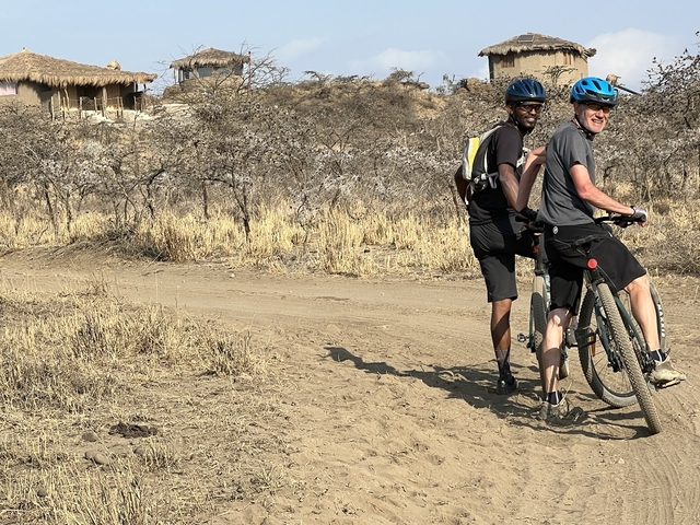 Two people biking on a dirt path in a dry landscape.