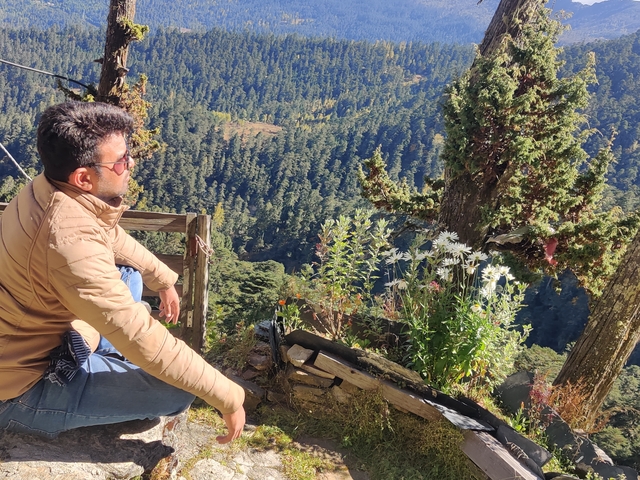 Person sitting and enjoying a view over forested mountains.
