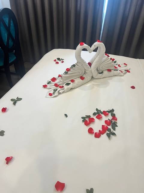 Bed with towel swans and flower petals for decoration.